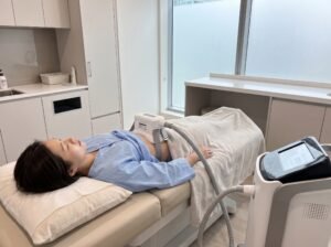 Cryolipolysis applicator attached to a client's abdomen on a treatment couch